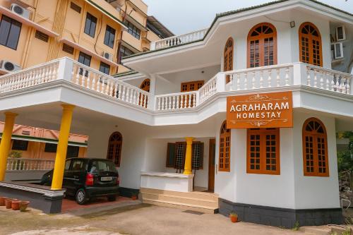 a white building with a sign in front of it at Guruvayur Agraharam Homestay in Guruvāyūr