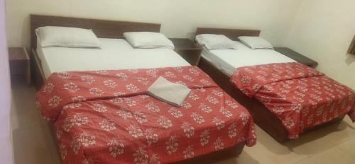 two beds in a small room with red sheets at Kathiyawadi Resort park view matheran in Matheran