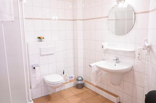 a white bathroom with a toilet and a sink at Hotel Gästehaus Lutgen in Waldfeucht