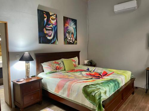 a bedroom with a bed with two paintings on the wall at An abundance of wildlife at Jungle Glory Home Abajo in Manuel Antonio