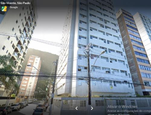 a tall white building with a tree in front of it at Linda Kitinete frente a praia in São Vicente