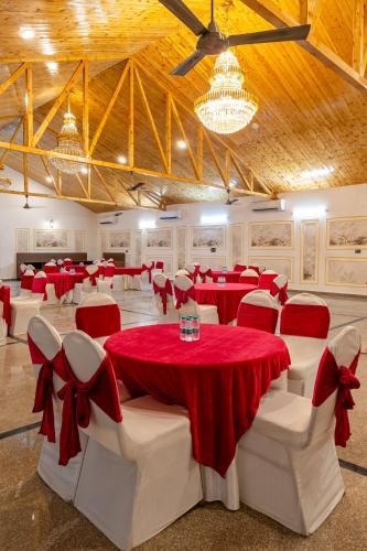 a banquet hall with red and white tables and chairs at Patio Farms by Saltstayz in Farrukhnagar