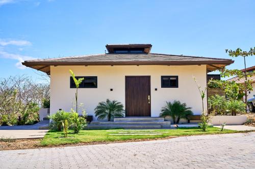 a small white house with a brown door at TreeCasa Hotel & Resort Nicaragua in San Juan del Sur