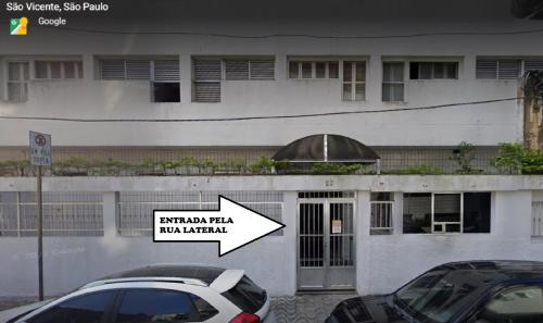 two cars parked in front of a building with a sign at Linda Kitinete frente a praia in São Vicente