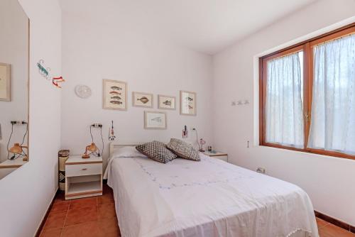 a white bedroom with a bed and a window at Casa Lola - Goelba in Capoliveri