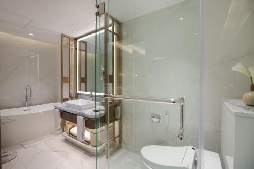 a bathroom with a shower and a toilet and a sink at Royal Ambarrukmo Yogyakarta in Yogyakarta