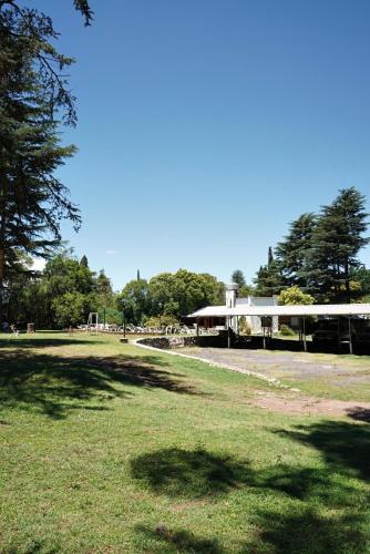 a park with a building and trees in the background at Cabañas Alvear in Huerta Grande