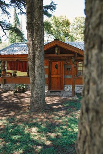 a log cabin with a tree in front of it at Cabañas Alvear in Huerta Grande
