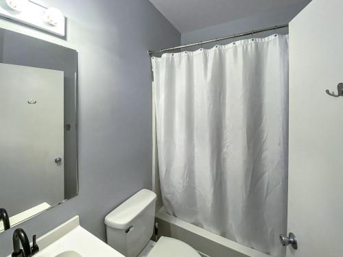 ein Badezimmer mit einem weißen Duschvorhang und einem WC in der Unterkunft Corporate Suite Midtown Wilmington in Wilmington