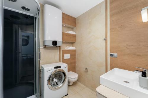 a bathroom with a washing machine and a toilet at Old Town Luxe Retreat - King Bed - Steps to Main Square in Kraków