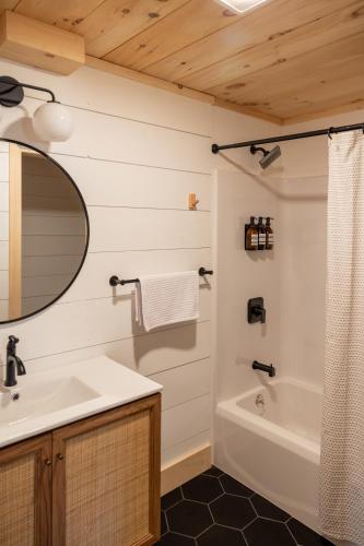 a bathroom with a sink and a tub and a mirror at Arrow Head Cabin in Killington
