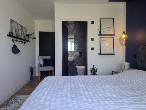 a bedroom with a large white bed and a door at Up Shed - Modern Countryside King-size Ensuite With Own Access in Bradworthy