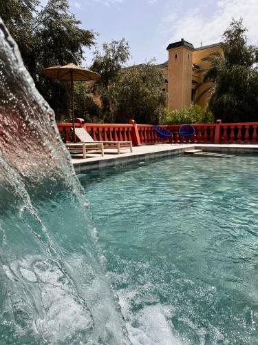 a swimming pool with a waterfall in front of a fountain at Villa Marrakchia - Palais d'hôtes & spa in Marrakech