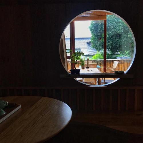 a round mirror in a room with a table and a window at Dan’s Sea Guest House Hangzhou in Hangzhou