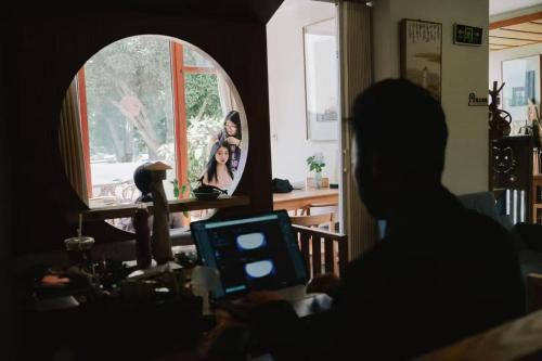 a person sitting in a room looking at a mirror at Dan’s Sea Guest House Hangzhou in Hangzhou