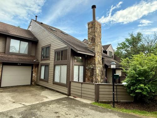 a house with a stone chimney and a garage at Seven Springs Hideaway Ski In and Out Pet Friendly in Champion
