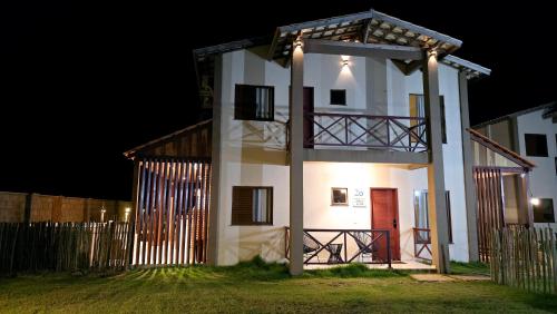 a white house with a red door at night at Casa BoxHome em Santo Amaro-MA in Santo Amaro