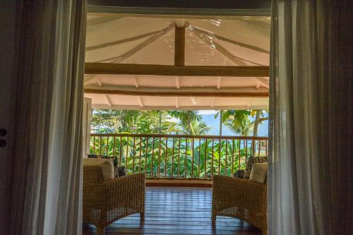 an open door to a porch with chairs and a balcony at TW Guaimbê Exclusive Suítes in Ilhabela