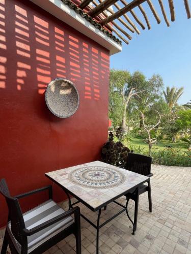 a table and chairs sitting next to a red wall at Domaine des Mimosas in Essaouira