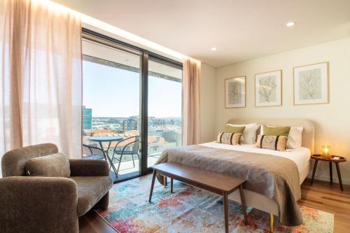 a bedroom with a bed and a chair and a large window at HILCROWN 39 Studios by LovelyStay in Vila Nova de Gaia