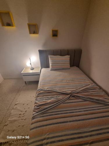 a bed with a striped blanket on it in a bedroom at Chez-moi in Sfax