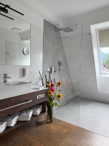 a bathroom with a sink and a vase of flowers at Seehotel Lilly in Strobl
