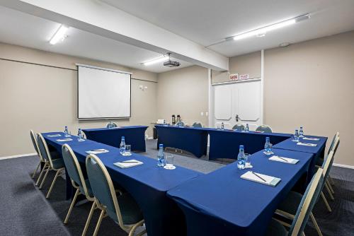 a conference room with blue tables and chairs and a screen at Slaviero Baia Norte Florianópolis in Florianópolis