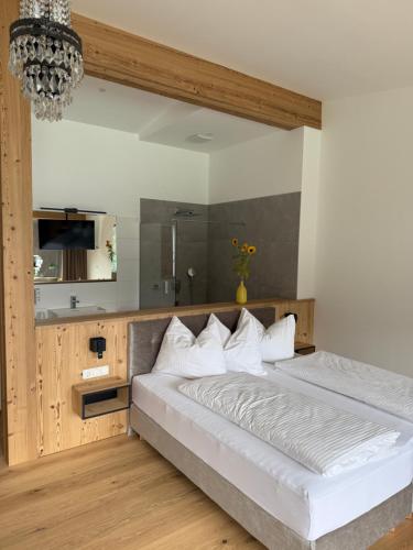 a bedroom with a large white bed and a kitchen at Seehotel Lilly in Strobl