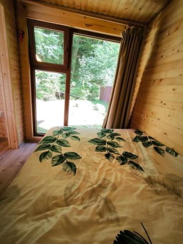 a bed in a room with a window at Cabana Padurea Cerbilor in Moara de Pădure