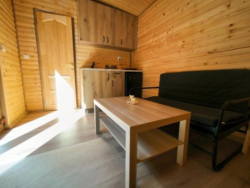 een kamer met een bank, een tafel en een koelkast bij Cabana Padurea Cerbilor in Moara de Pădure