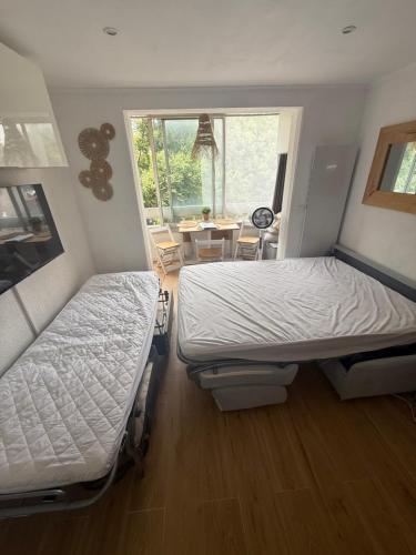 - 2 lits dans une chambre avec une table et une fenêtre dans l'établissement Studio cosy à 200m de la mer!, à Saint-Raphaël