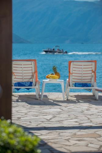 two chairs and a table on a beach with the ocean at Apartments Babilon in Kotor