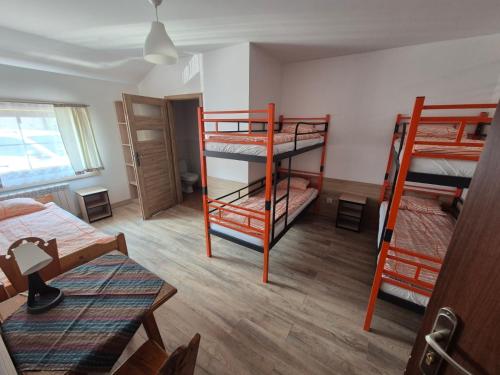 a room with three bunk beds and a table at Zajazd PTTK Pod Roztoką in Rytro