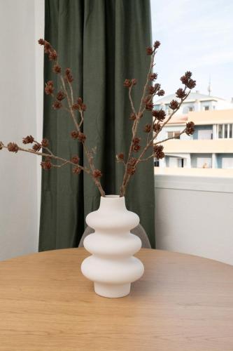 a white vase with branches in it on a table at Brisas de Güimar in Santa Cruz de Tenerife
