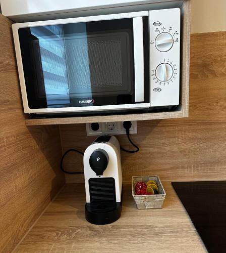 a microwave sitting on top of a counter next to a bowl of fruit at CentROOM Nagykanizsa in Nagykanizsa