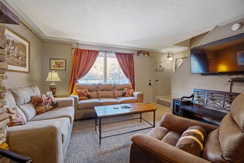 a living room with couches and a flat screen tv at Luxury Condo Tucked in the Heart of Killington in Killington