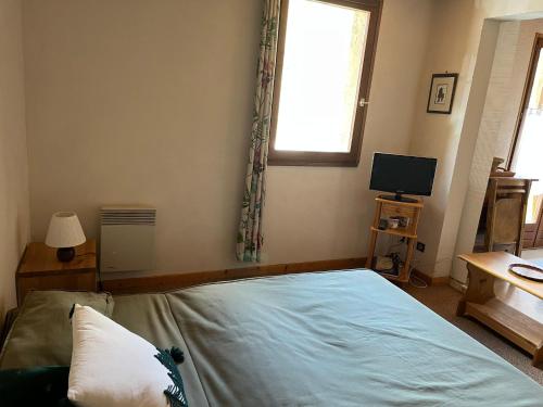 a bedroom with a bed and a window and a television at Les Soleils de la Meije in La Grave