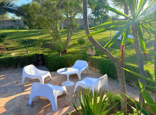 a patio with white chairs and a table at Domaine des Mimosas in Essaouira