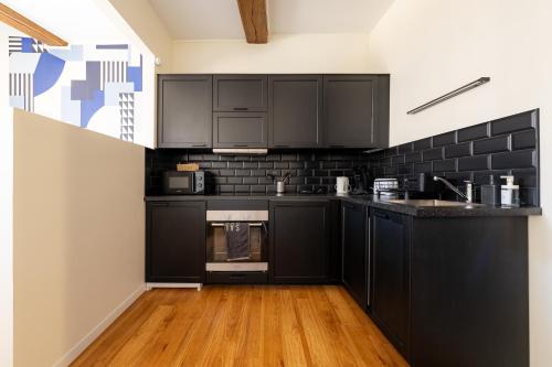 a kitchen with black cabinets and a wooden floor at Best Place - Studio hyper centre ville d'Arras in Arras