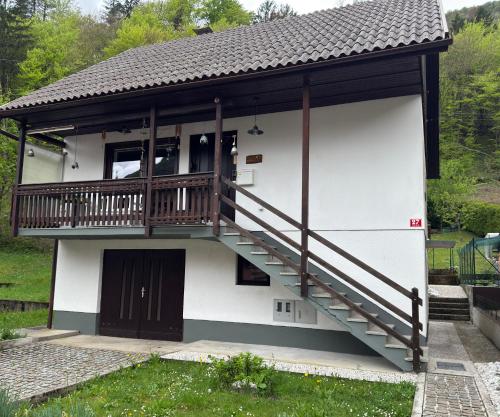 a white house with a balcony and a staircase at Hisa Lina Near Bovec in Srpenica