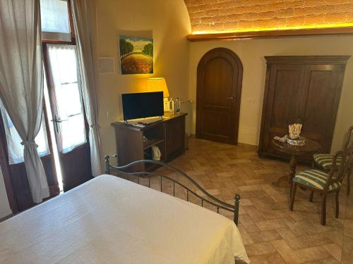 a bedroom with a bed and a tv and a chair at Fattoria Fibbiano in Terricciola