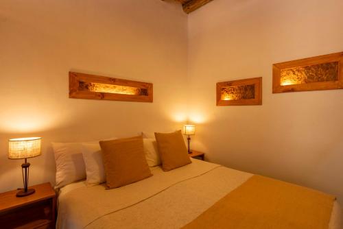 a bedroom with a bed and two lights on the wall at Tala Huasi in Tilcara