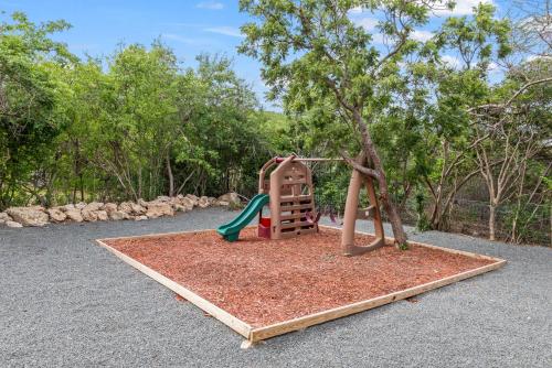 a playground with a slide and a tree at Vista Papaya Suites in Westpunt