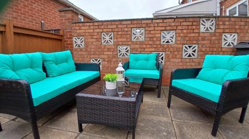 a patio with blue cushioned chairs and a table at Stylish Seaside Cottage - 3 minute walk to beach with parking in Skegness