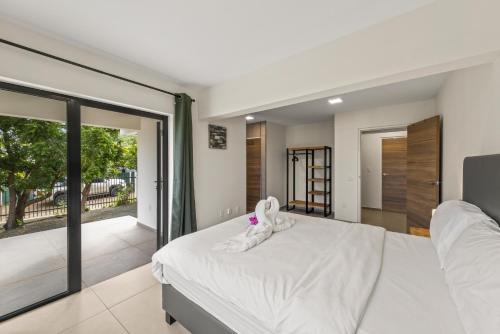 a bedroom with a large white bed and sliding glass doors at Vista Papaya Suites in Westpunt