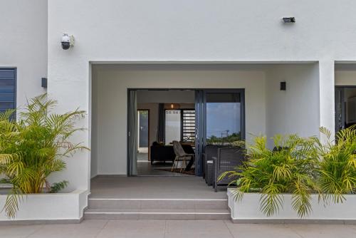 a white house with glass doors and plants at Vista Papaya Suites in Westpunt