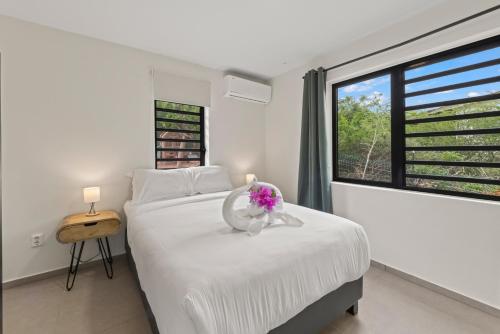 a white bedroom with a bed with flowers on it at Vista Papaya Suites in Westpunt