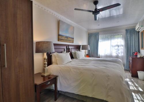 a bedroom with a large bed and a ceiling fan at The Victoria House in Ficksburg