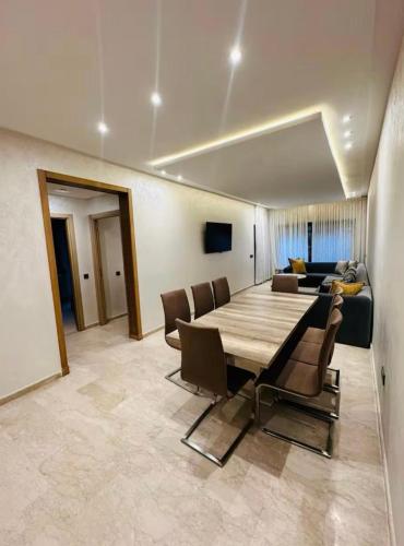 a dining room with a table and chairs and a couch at appartement de luxe au rez de jardin avec piscine privative in Tamaris