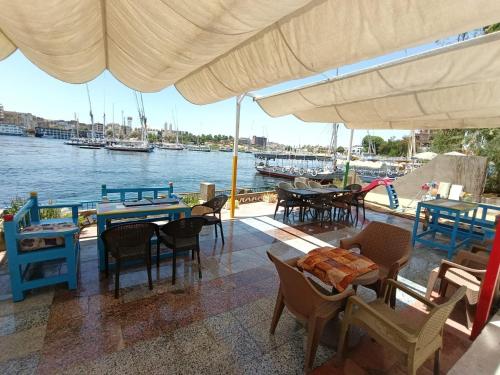 a patio with tables and chairs and a view of the water at New El Amin Guesthouse in Aswan